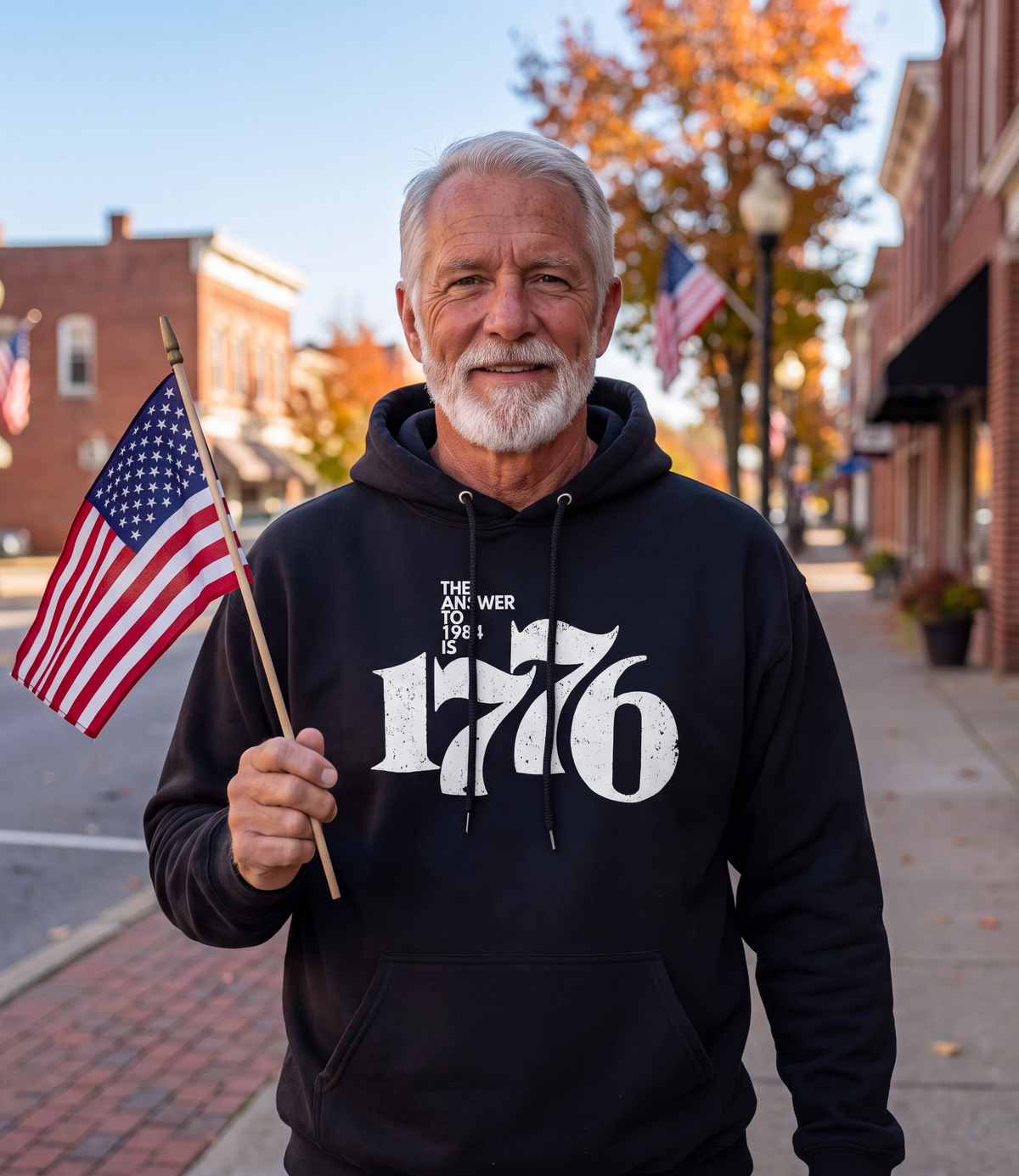 Man wearing The Answer To 1984 Is 1776 Hoodie in black on a flag-lined Main Street