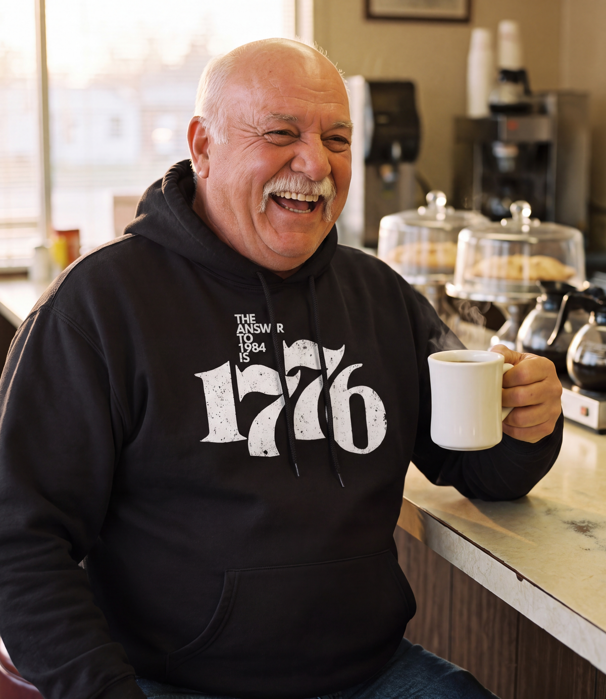 Man wearing The Answer To 1984 Is 1776 Hoodie in black at a diner counter
