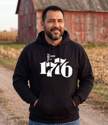 Man wearing The Answer To 1984 Is 1776 Hoodie in black on a farm road by a red barn